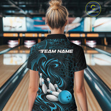 Load image into Gallery viewer, Female model standing in a bowling lane showing the back of a black and blue bowling polo shirt with a tribal flame bowling ball and pins graphic.