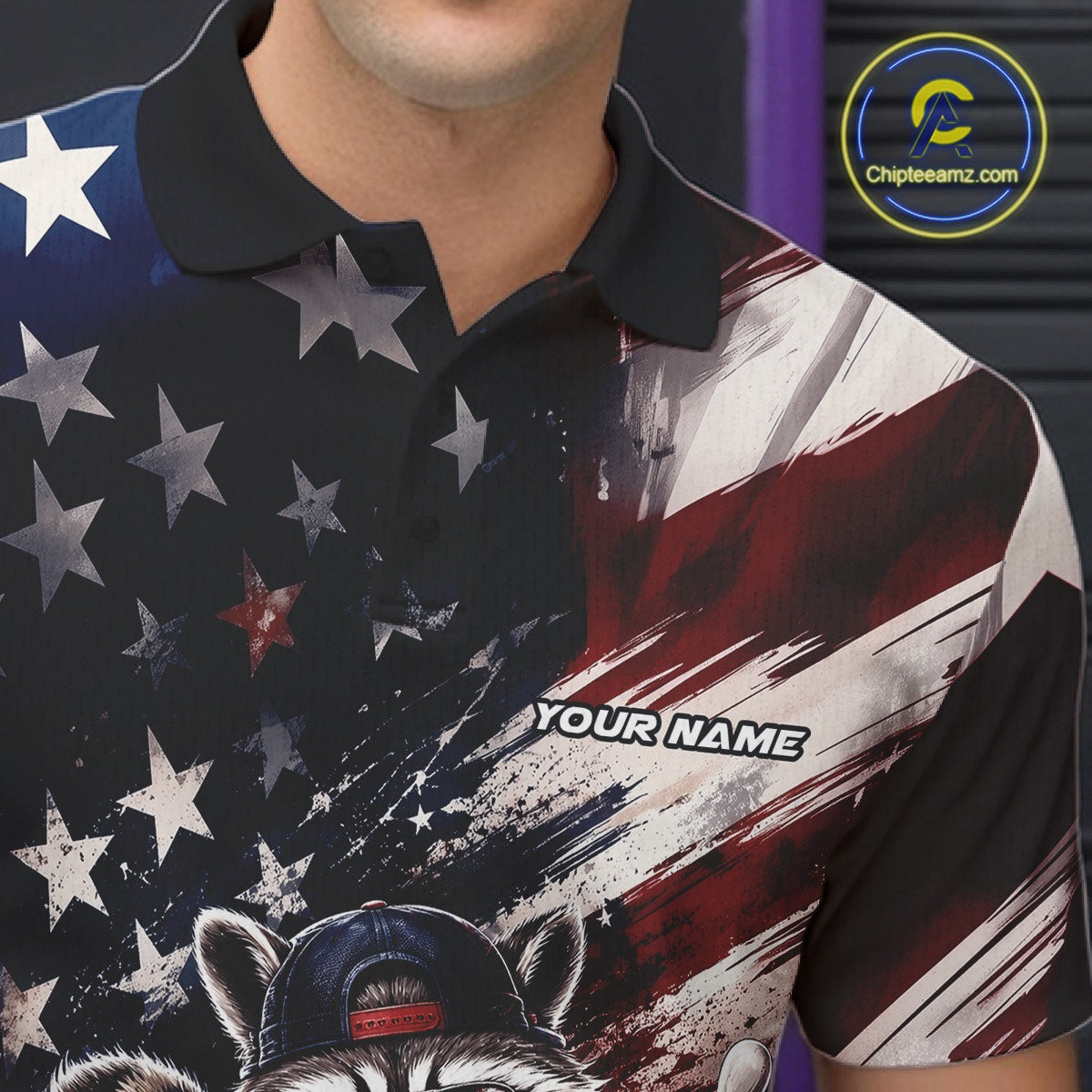 Close-up of the left chest on a bowling polo shirt featuring a raccoon in patriotic sunglasses rolling a bowling ball through scattered pins with a distressed American flag backdrop.