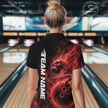 Load image into Gallery viewer, Back view of a female model wearing a black bowling polo shirt in a bowling alley featuring a skull clutching a bowling ball with swirling red energy flames