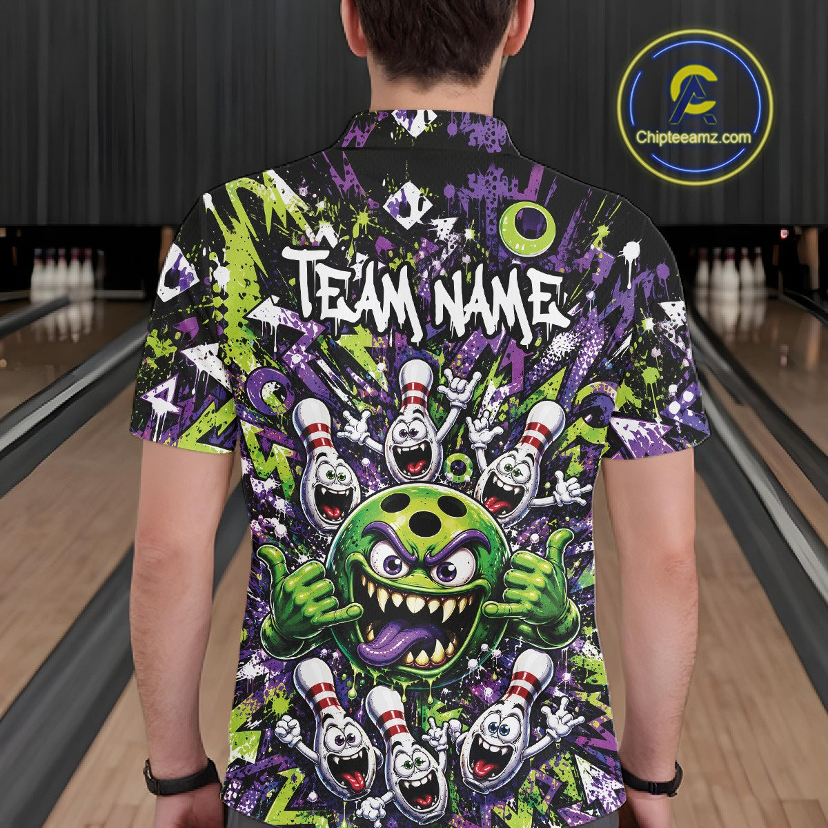 Back view of a male model wearing a green and purple bowling polo shirt in a bowling lane, featuring a mischievous green monster bowling ball with sharp teeth, a purple tongue, playful hand gesture, and cheerful cartoon bowling pins.