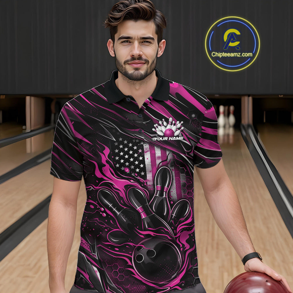 Male model at a bowling lane wearing a black and pink bowling polo shirt with a patriotic flaming bowling ball striking pins and American flag graphics.