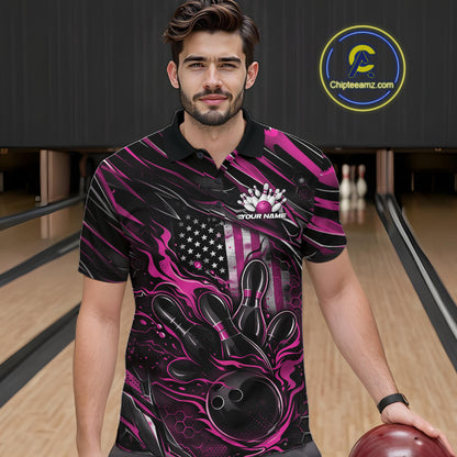 Male model at a bowling lane wearing a black and pink bowling polo shirt with a patriotic flaming bowling ball striking pins and American flag graphics.