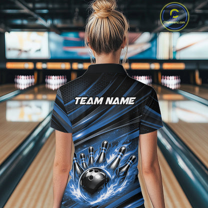 Female model at a bowling lane, back view of black and blue quarter zip shirt showcasing fiery bowling ball striking pins with abstract stripe accents