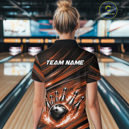 Back view of a female model in a bowling alley wearing a black and orange polo shirt featuring a fiery bowling action scene.
