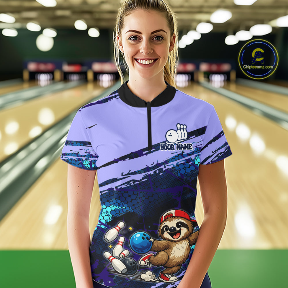 Person wearing a bowling-themed shirt with a sloth character in a bowling alley.