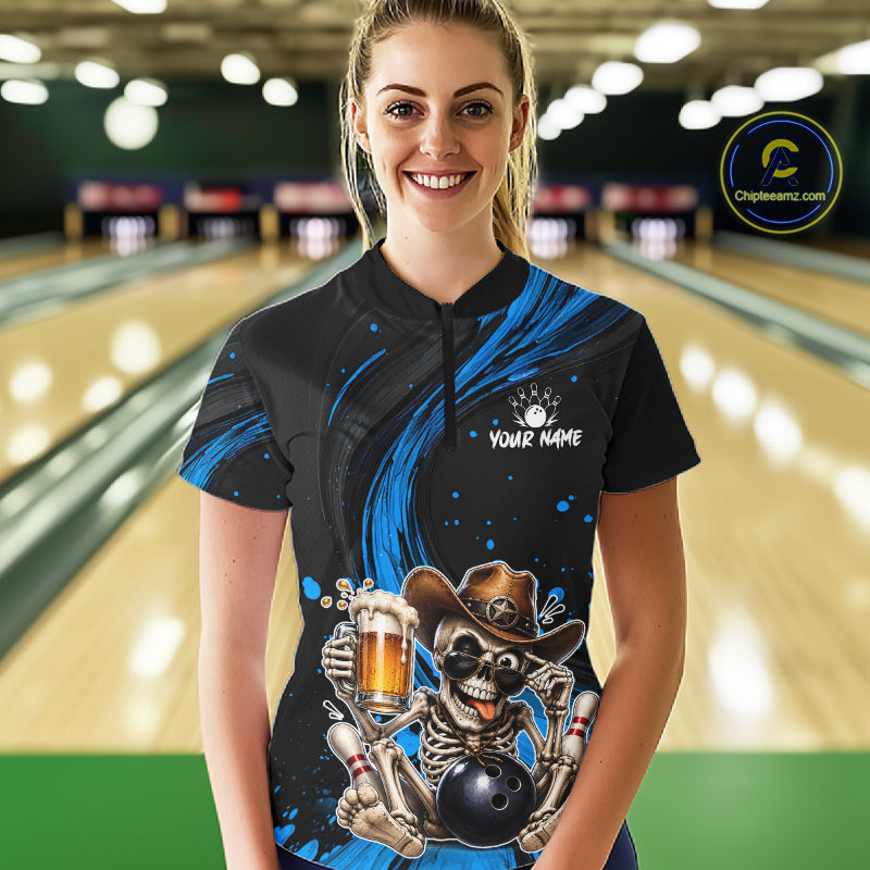Person wearing a black and blue bowling shirt with a skeleton design in a bowling alley.