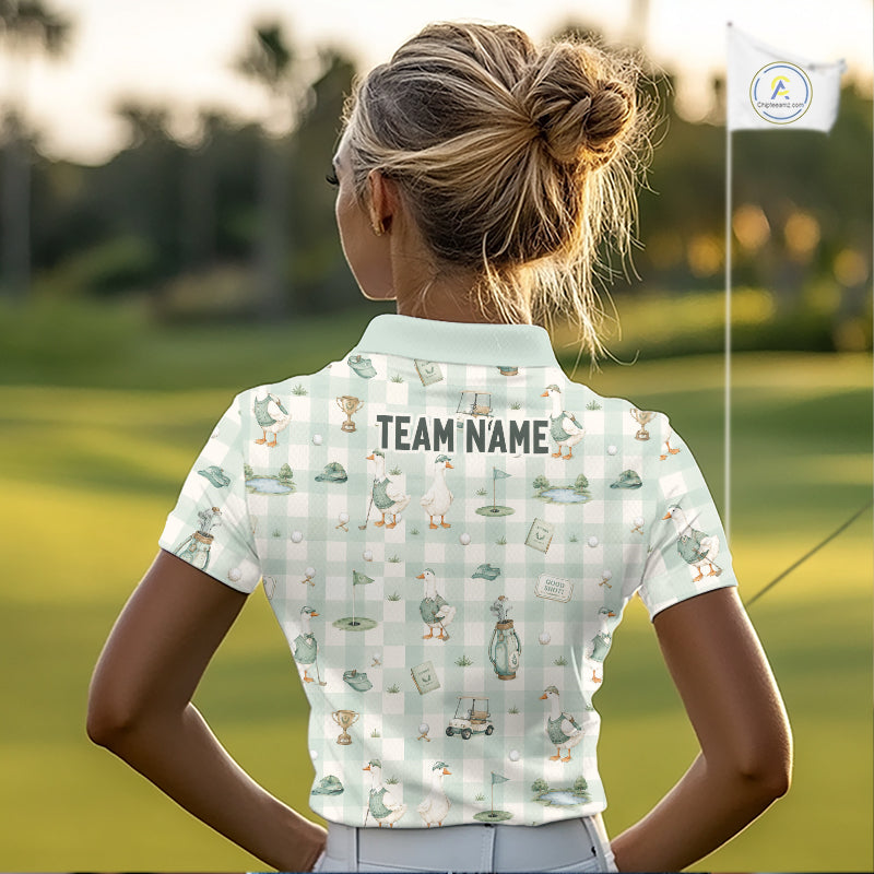 A woman on a golf course seen from behind, wearing a short-sleeve polo shirt with a white and light green gingham pattern, golf-themed illustrations, and 'TEAM NAME' printed across the back.