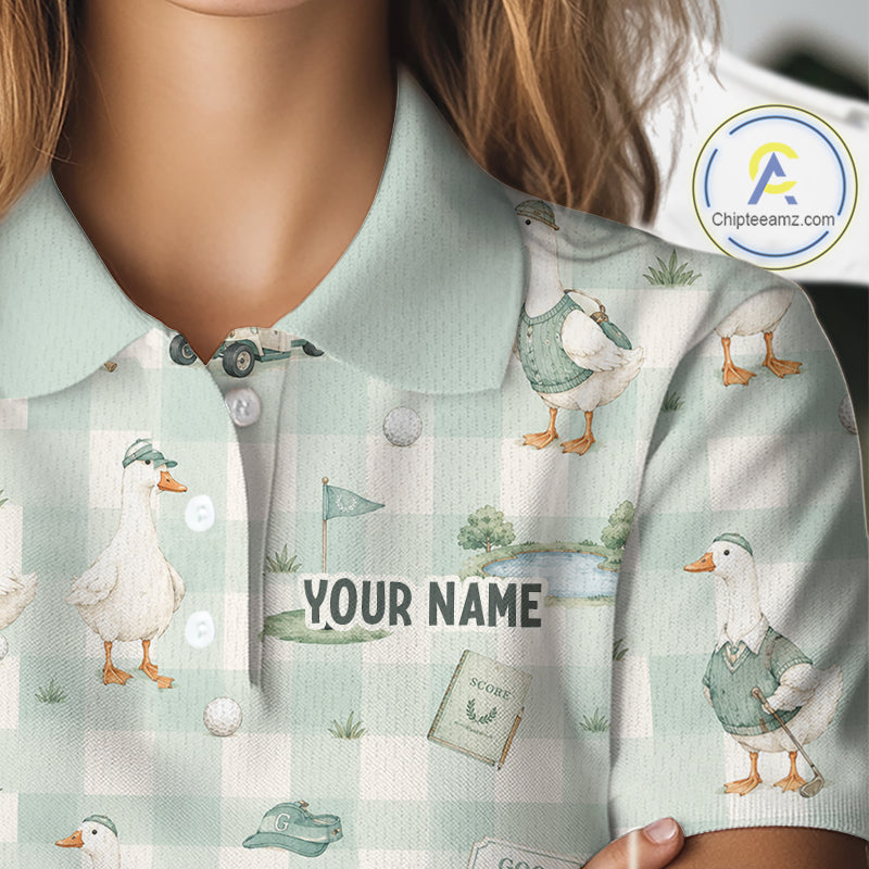 A close-up of a person wearing a short-sleeve polo shirt with a pale mint green and white gingham pattern, printed with duck illustrations, a golf flag, a golf cart, and the text 'YOUR NAME' across the chest. A circular 'Chipteamz.
