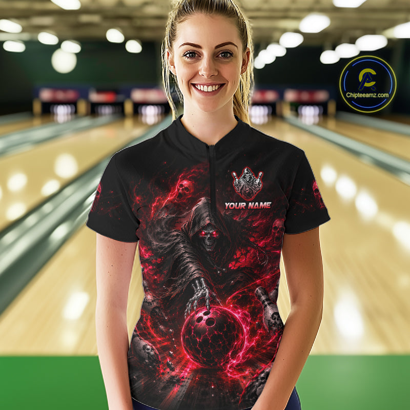 Woman wearing a black bowling shirt with red and black design in a bowling alley.