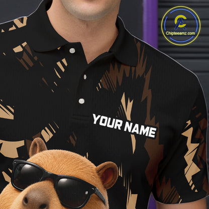 Black polo shirt with gold abstract design and 'Your Name' text, worn by a person, with a capybara wearing sunglasses in the foreground.