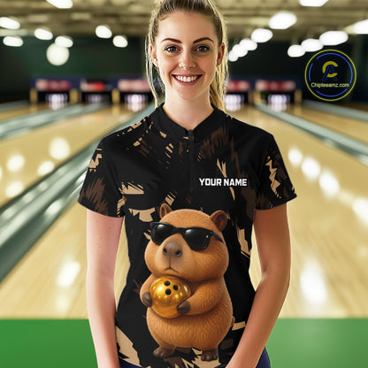 Person wearing a bowling shirt with a capybara design and 'Your Name' text in a bowling alley.