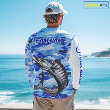 Load image into Gallery viewer, Person wearing a wahoo fishing shirt long sleeve with a wahoo fish design and 'TEAM NAME' text on the back, standing by the ocean.