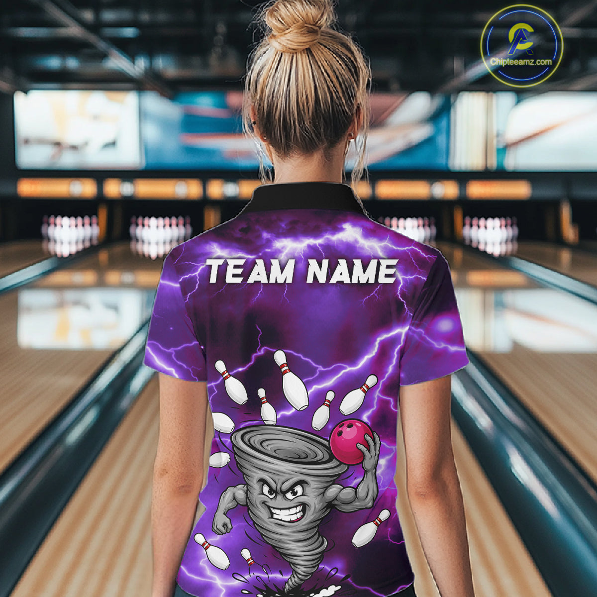 Back view of woman wearing a purple thunder lightning tornado bowling polo shirt inside a bowling alley.