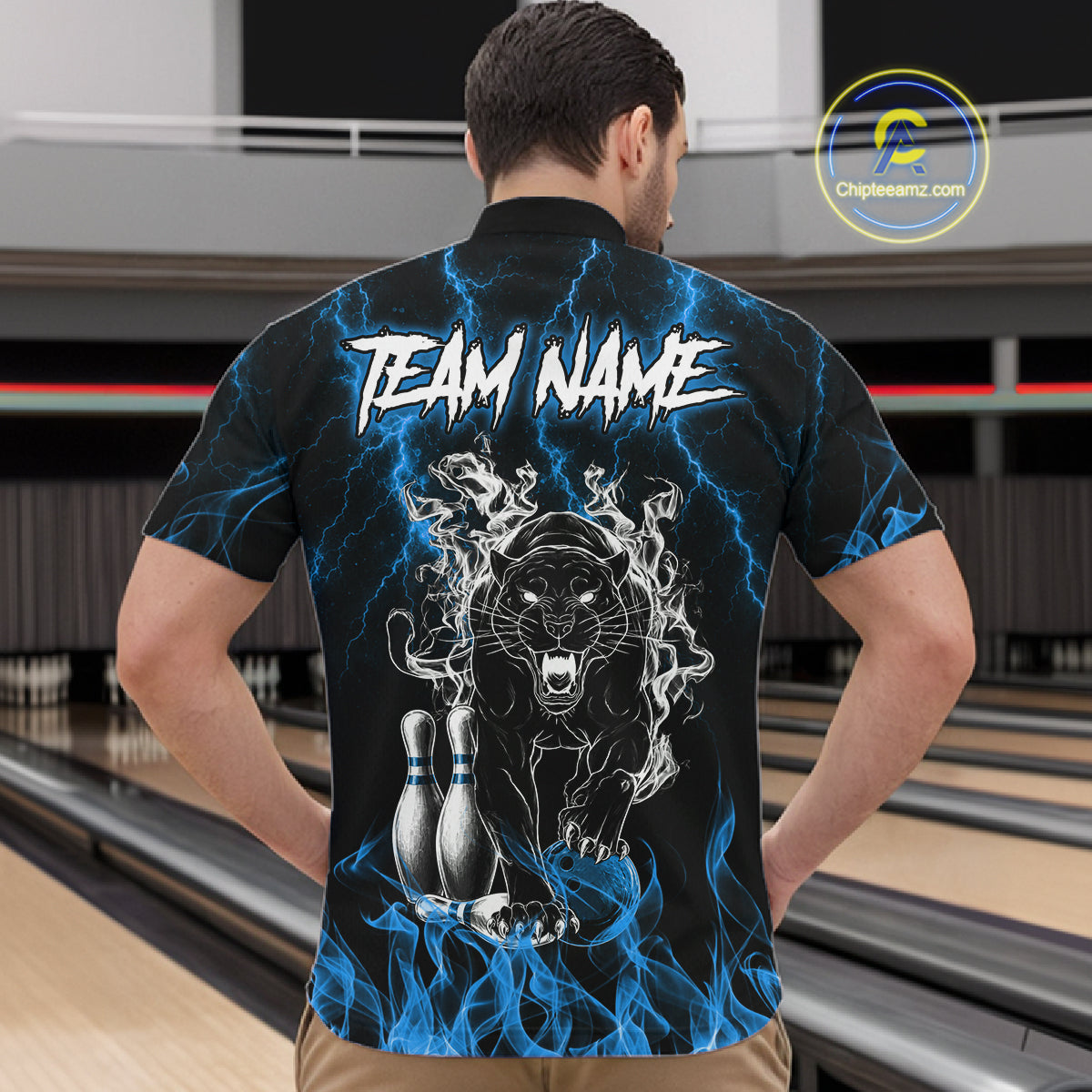Back view of man wearing a blue flaming panther bowling quarter zip shirt in a bowling alley.