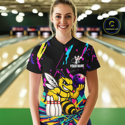 Person wearing a black bowling shirt with colorful design and bee graphic in a bowling alley.
