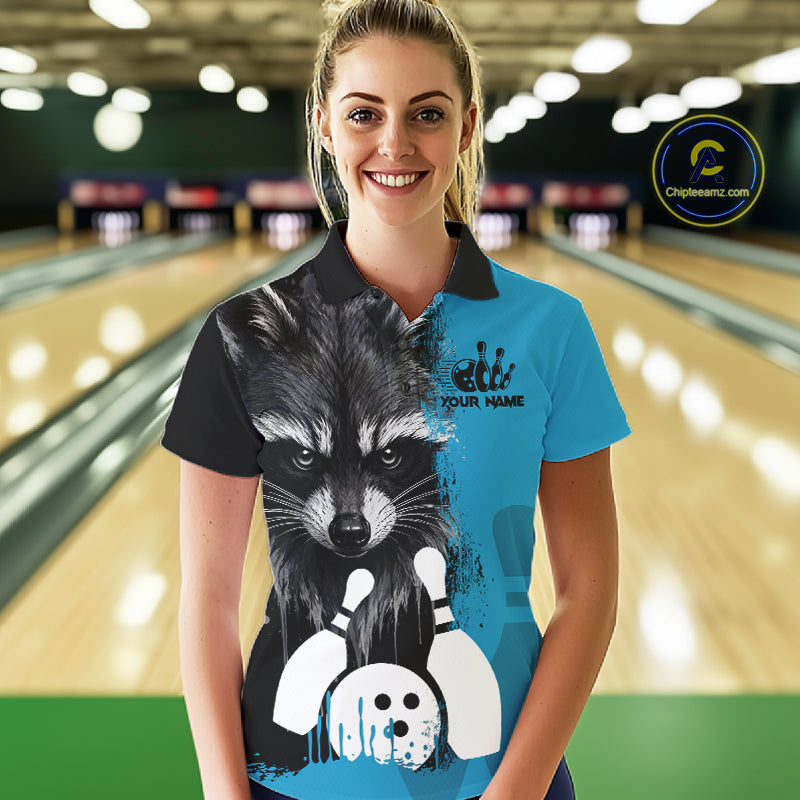 Woman wearing a black and blue raccoon bowling polo shirt at a bowling alley front view.