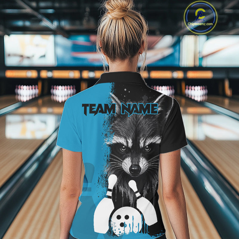 Back view of woman wearing a black and blue raccoon bowling polo shirt inside a bowling alley.
